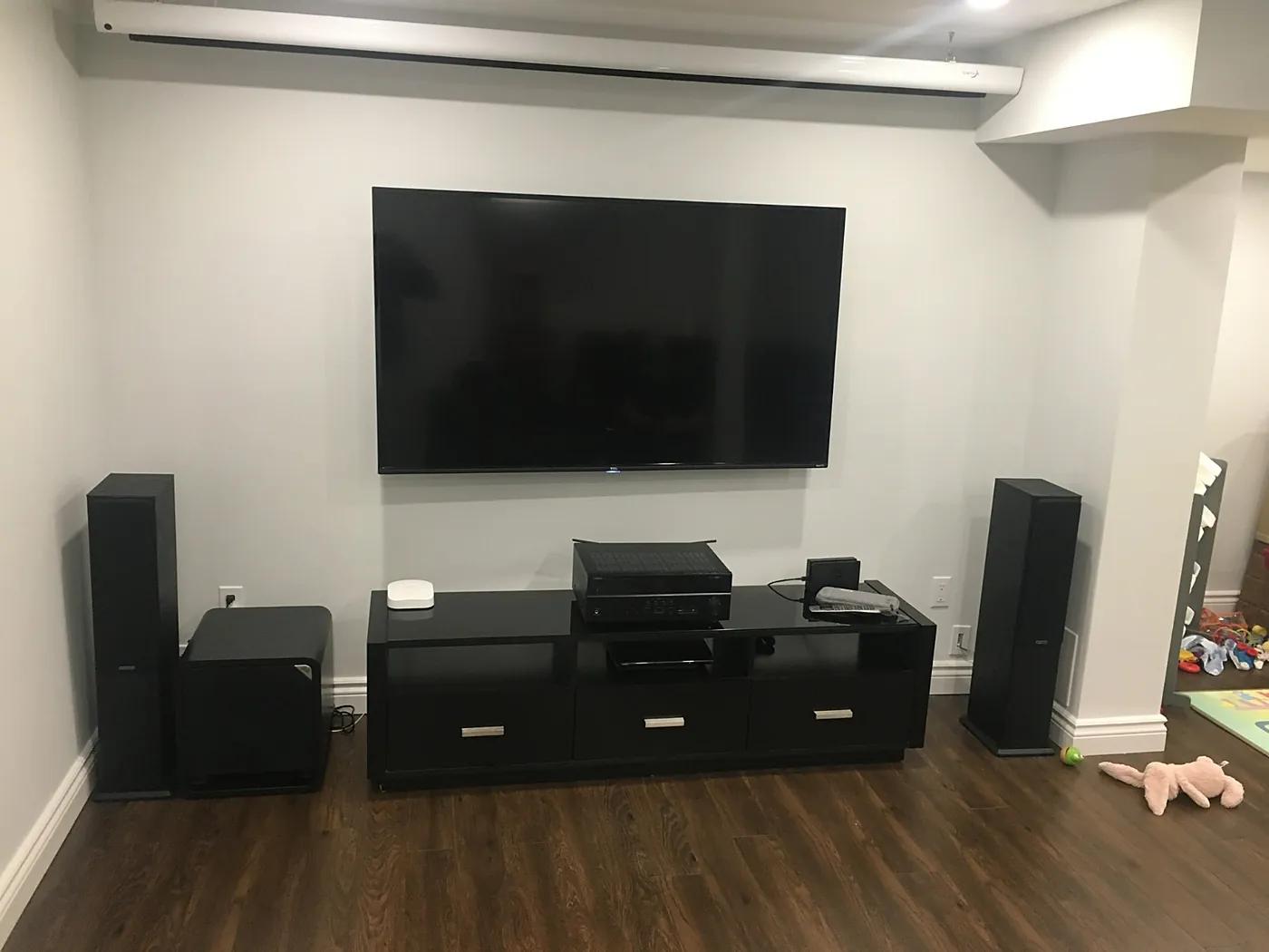 Wall-mounted TV with tower speakers and an AV console in a living room